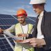 Engineer and businessman in hard hats discussing a solar energy project during a customer consultation.