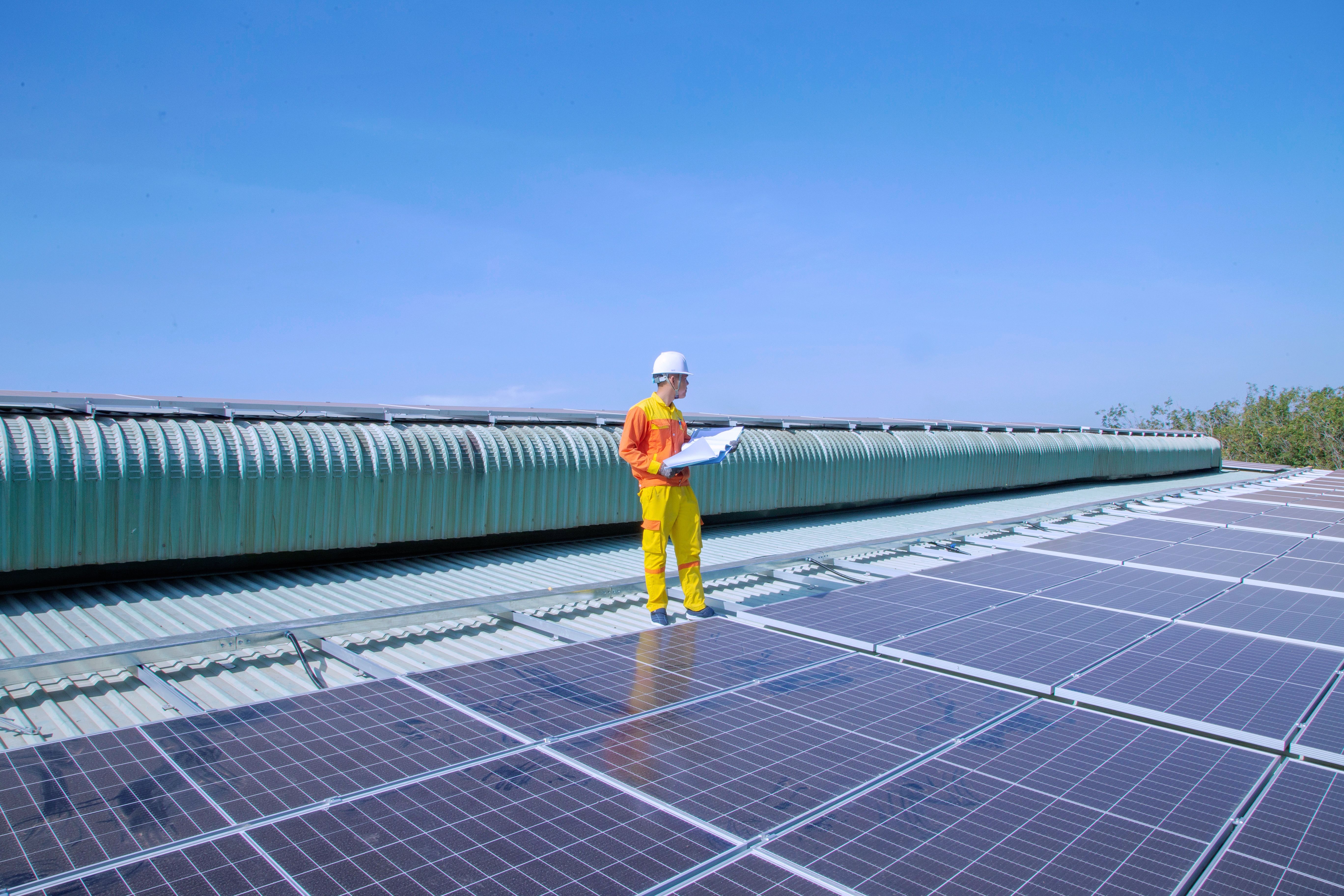 Technician examining solar panels on a rooftop during a system inspection.
