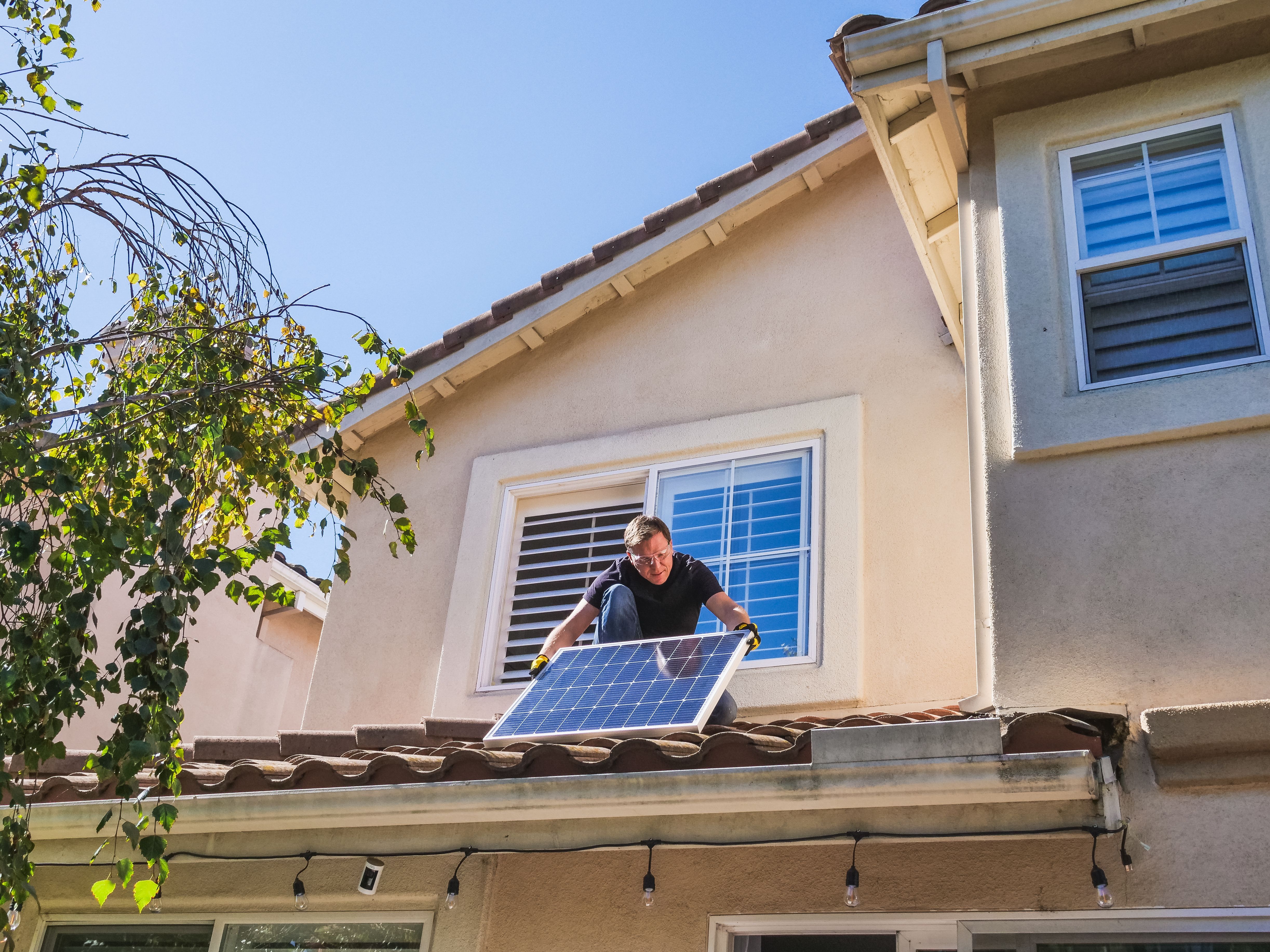 Solar technician installing photovoltaic panels on a sunny residential rooftop.